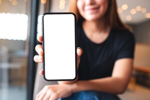 Mockup image of a beautiful asian woman holding and showing a mobile phone with blank white screen