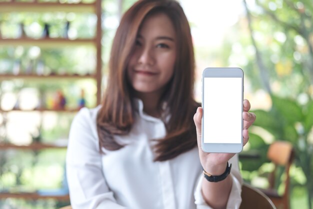 Mockup image of a beautiful woman holding and showing white mobile phone