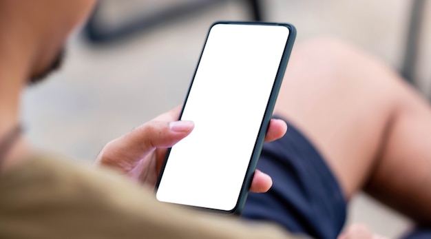 Mockup image blank white screen cell phone.men hand holding texting using mobile on desk at home office.