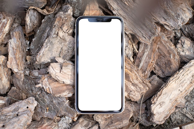 Mockup image blank white screen modern cell phone outdoors on the background of pine bark. background empty space for advertise text