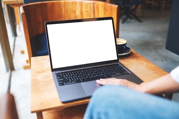 Mockup image of a businesswoman using and touching on laptop touchpad with blank white desktop screen in cafe