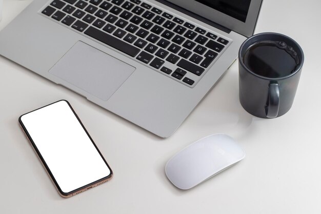 Mockup image cell phone computer and typing with blank screen for textusing laptop contact business searching information in workplace on desk in officedesign creative work space on wooden desktop