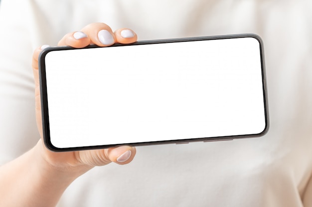 Mockup image of female hand holding and showing black mobile phone with blank screen. Close-up