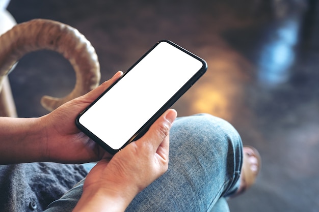 Mockup image of a hand holding black mobile phone with blank white desktop screen