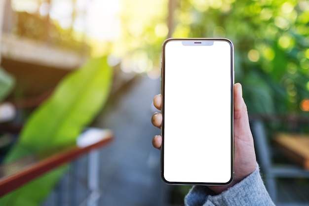 Mockup image of a hand holding and showing black mobile phone with blank desktop screen