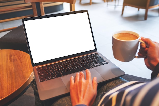Макет изображения руки, касающейся сенсорной панели ноутбука с пустым белым экраном рабочего стола во время питья кофе