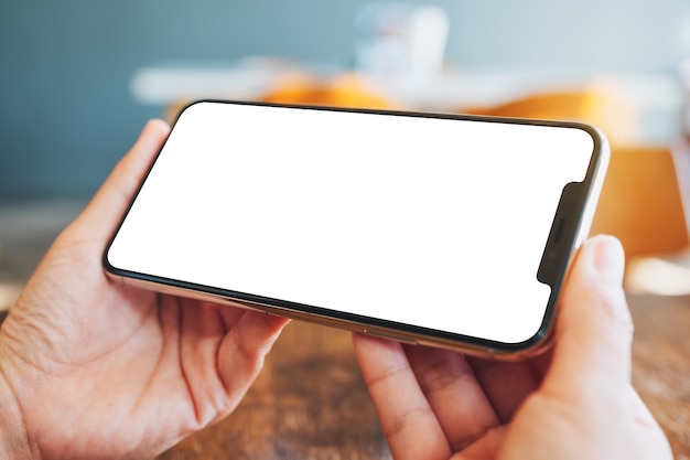 Mockup image of hands holding black mobile phone with blank desktop screen