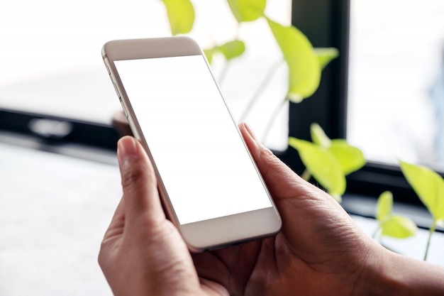 Immagine del modello delle mani che tengono il telefono cellulare bianco con lo schermo in bianco