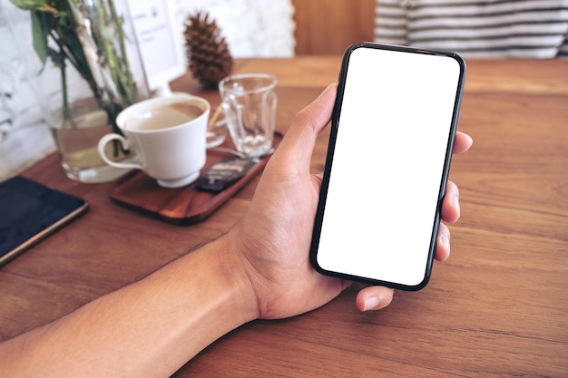 Mockup image of a man's hand holding black mobile phone with blank screen with woman in cafe