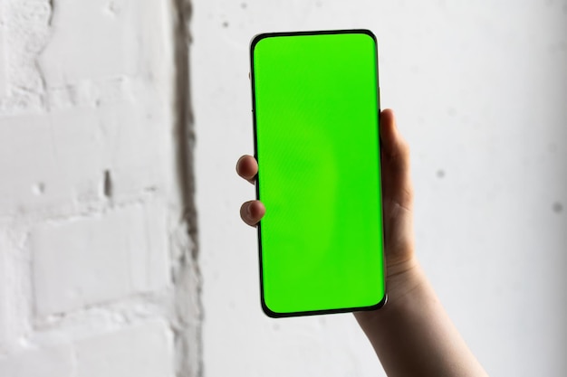 Photo mockup image of a person holding smart mobile phone with blank green screen