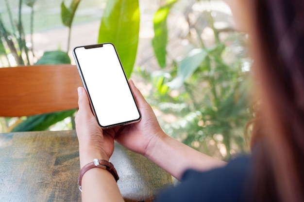 Mockup image of a woman holding black mobile phone with blank desktop screen