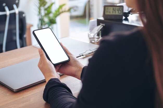 Foto immagine di mockup di una donna che tiene un telefono cellulare nero con schermo bianco vuoto