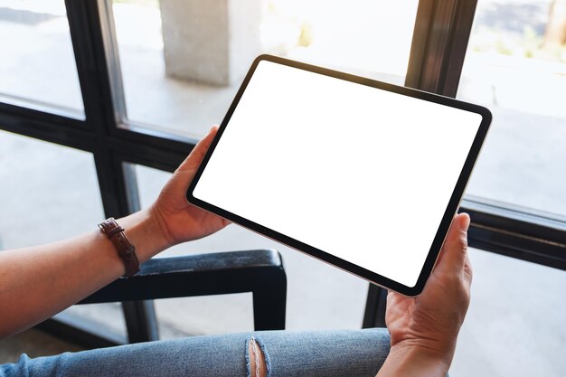 Mockup image of a woman holding black tablet pc with blank white desktop screen