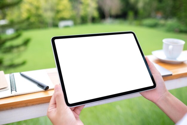 Mockup image of a woman holding digital tablet with blank white desktop screen in the outdoors