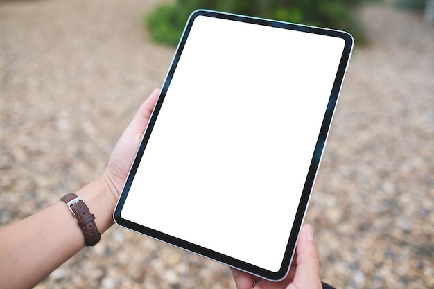 Mockup image of a woman holding digital tablet with blank white desktop screen in the outdoors