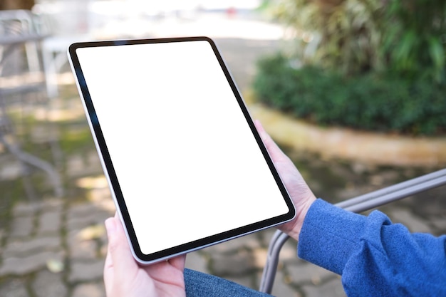 Mockup image of a woman holding digital tablet with blank white desktop screen in the outdoors