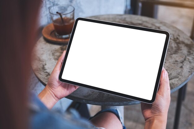 空白の白いデスクトップ画面でデジタルタブレットを保持している女性のモックアップ画像
