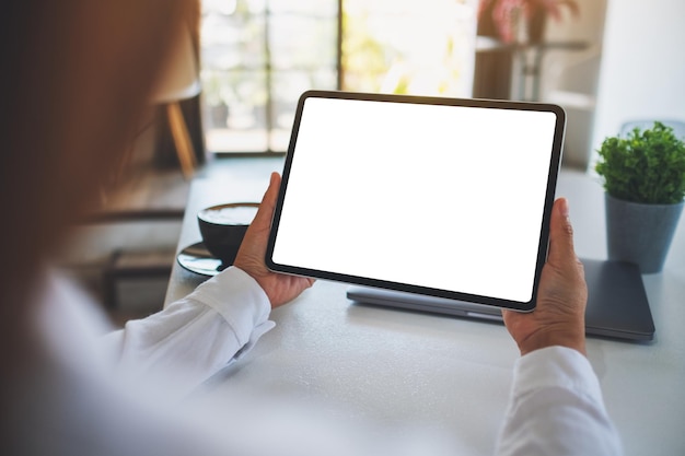 空白の白いデスクトップ画面でデジタルタブレットを保持している女性のモックアップ画像