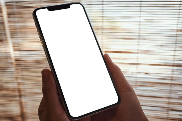 Mockup image of a woman holding mobile phone with blank white desktop screen