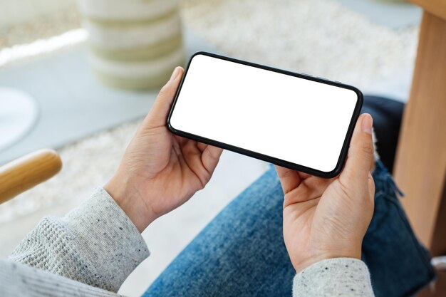 Mockup image of a woman holding mobile phone with blank white desktop screen