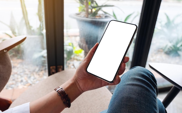 Foto immagine mockup di una donna che tiene in mano un telefono cellulare con uno schermo desktop bianco vuoto
