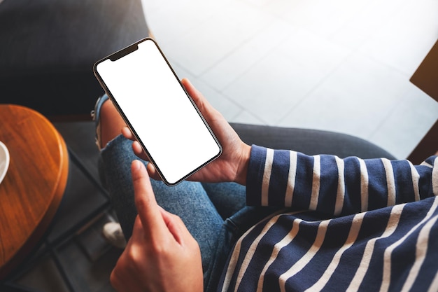 Mockup image of a woman holding mobile phone with blank white desktop screen