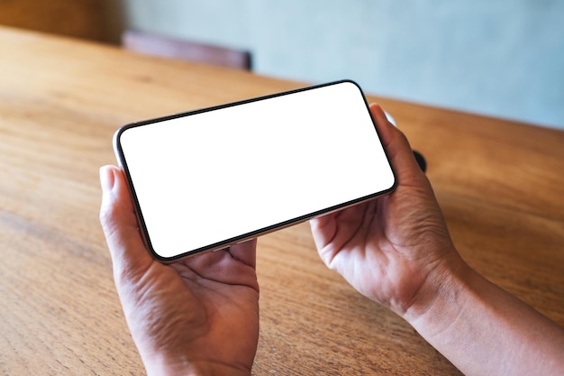 Mockup image of a woman holding mobile phone with blank white desktop screen