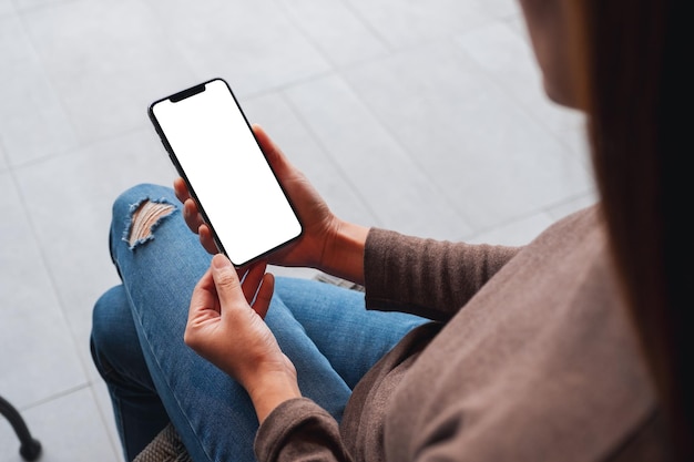 Photo mockup image of a woman holding mobile phone with blank white desktop screen