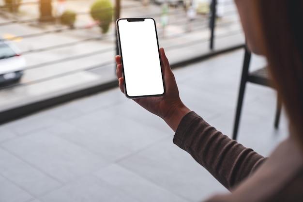 Mockup image of a woman holding mobile phone with blank white desktop screen