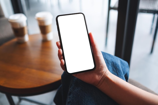 Mockup image of a woman holding mobile phone with blank white desktop screen