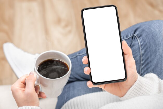 Immagine del modello di una donna che tiene e utilizzando il telefono cellulare nero con lo schermo del desktop vuoto