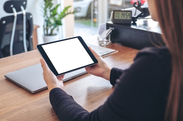 Mockup image of a woman holding and using black tablet pc with blank white desktop screen