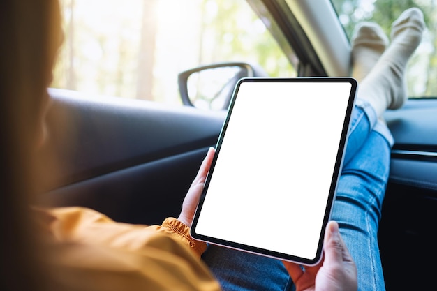 차에 누워 있는 동안 빈 화면이 있는 디지털 태블릿을 들고 사용하는 여성의 모형 이미지