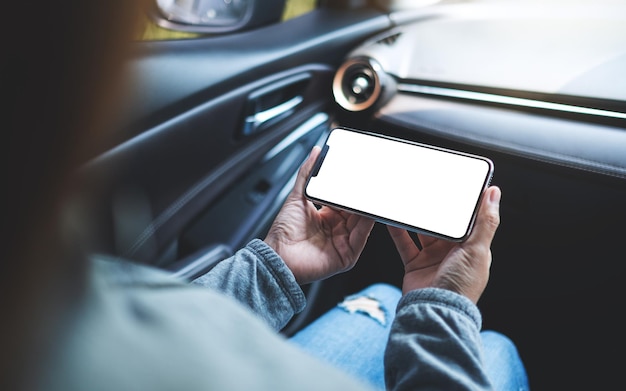 車の中で空白の画面で携帯電話を持って使用している女性のモックアップ画像