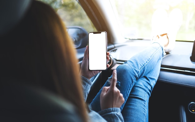 車の中で空白の画面で携帯電話を持って使用している女性のモックアップ画像