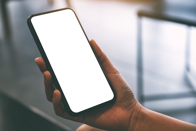 Mockup image of a woman's hand holding black mobile phone with blank desktop screen