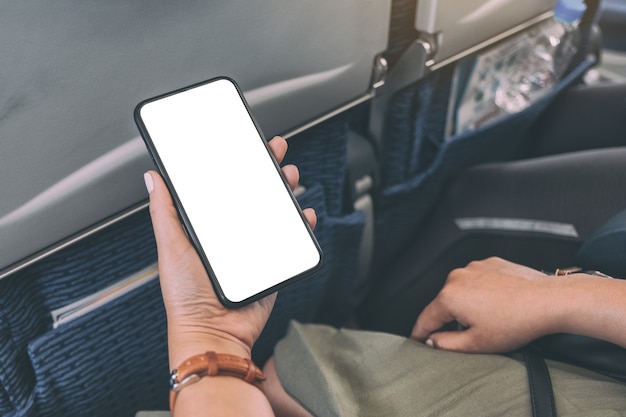 mockup image of woman's hand holding a black smart phone with blank desktop screen in cabin
