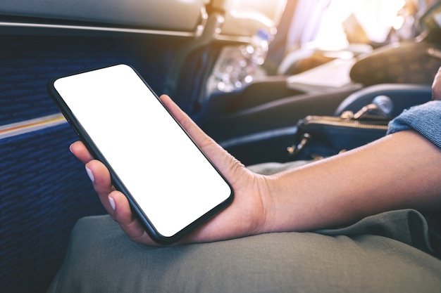 Mockup image of woman's hand holding a black smart phone with blank desktop screen in cabin