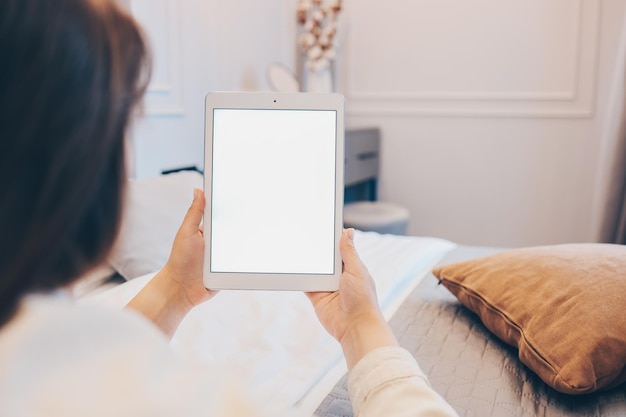 Mockup image of woman's hand holding white tablet pc with blank white screen at home