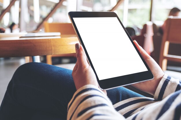 Mockup image of woman's hands holding black tablet pc with blank white desktop screen while sitting in cafe