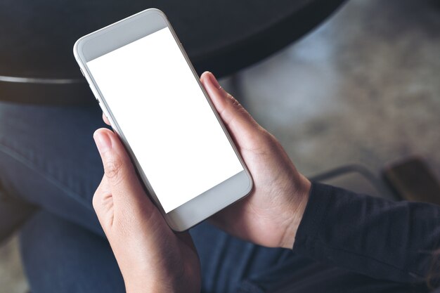 Mockup image of woman's hands holding white mobile phone with blank desktop screen 