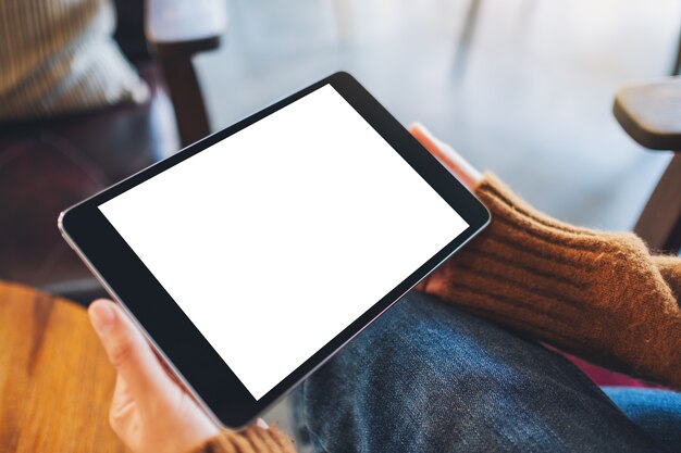 Mockup image of a woman sitting and holding black tablet pc with blank white desktop screen