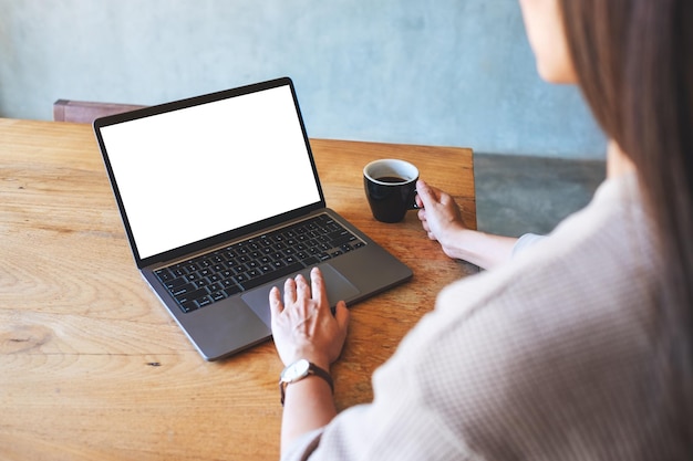 커피를 마시는 동안 빈 흰색 바탕 화면이 있는 노트북 컴퓨터 터치패드를 만지는 여성의 모형 이미지