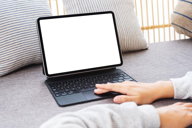 Mockup image of a woman using tablet pc with blank desktop white screen as a computer pc on sofa at home