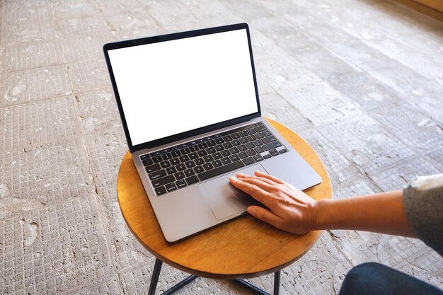 Mockup image of a woman using and touching on laptop computer touchpad with blank white desktop screen on the table