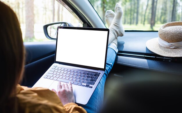 Mockup image of a woman using and typing on laptop computer with blank desktop screen while laying in the car