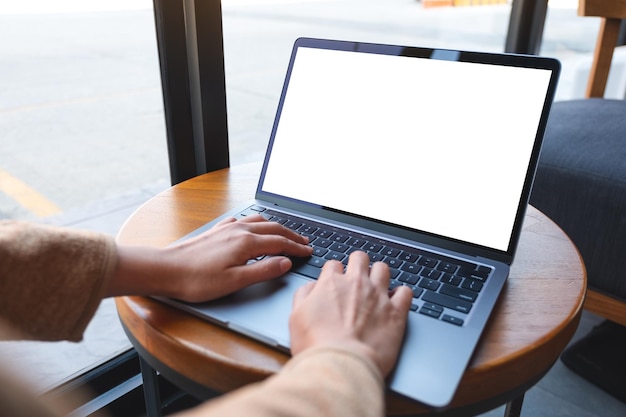 Mockup image of a woman using and typing on laptop computer with blank white desktop screen in cafe