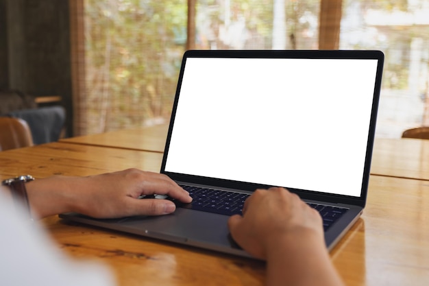 Mockup image of a woman using and typing on laptop computer with blank white desktop screen on wooden table