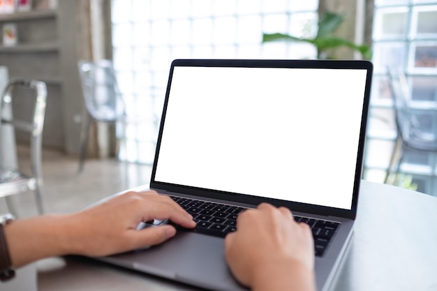 Mockup image of a woman using and typing on laptop computer with blank white desktop screen