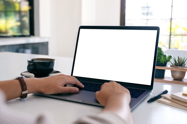 Immagine mockup di una donna che utilizza e digita sul computer portatile con schermo desktop bianco vuoto su un tavolo di legno